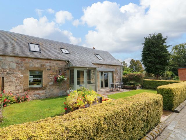 A garden view of a stone cottage with patio and flowerbed at Muirmailing Cottage Plean near Stirling