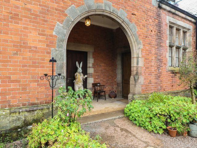 An outdoor entry area with a bench and a rabbit statue at Shrewsbury Lodge in Great Haywood