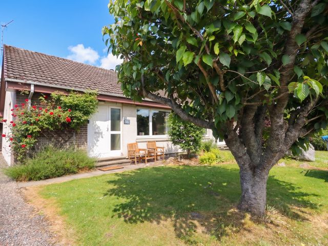 A house with a garden and seating area at Steam Cottage in Aviemore