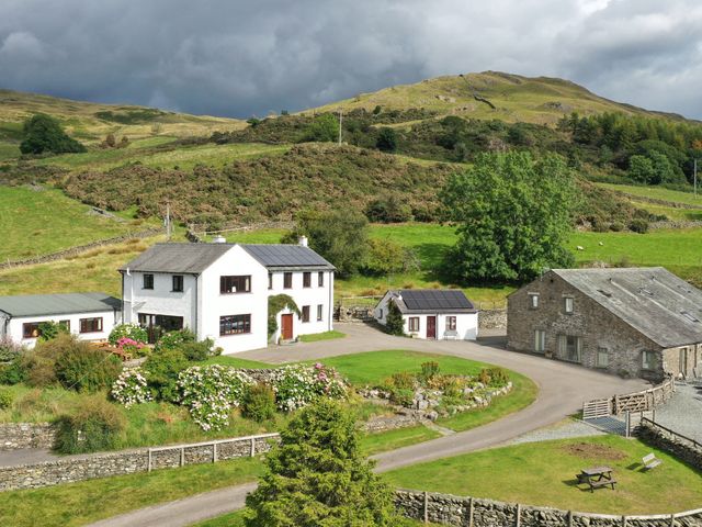 A rural property with white and stone buildings surrounded by gardens and hills at Ghyll Bank Bungalow Staveley near Windermere