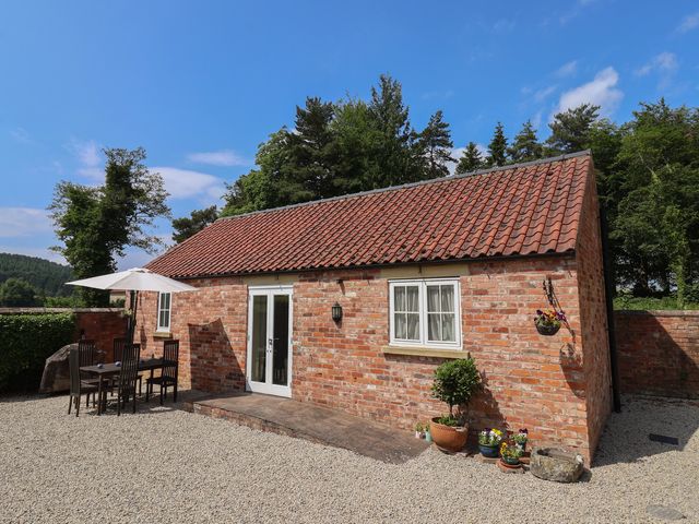 An outdoor area with a brick building, table and chairs at Stable Cottage in Cawton near Hovingham
