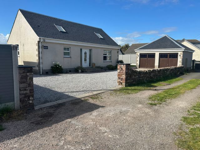 A house with a garage and gravel driveway at The Bothy in Southerness