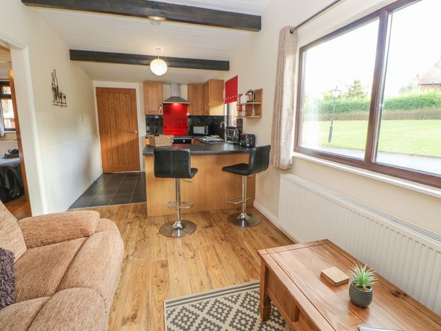 A kitchen and living area with stools a sofa and a window at Bluebell Lodge in Saltburn-by-the-Sea