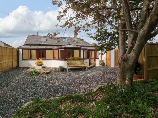 A garden with a house, bench, tree and gravel at Ty Taid in Llanddaniel Fab near Beaumaris