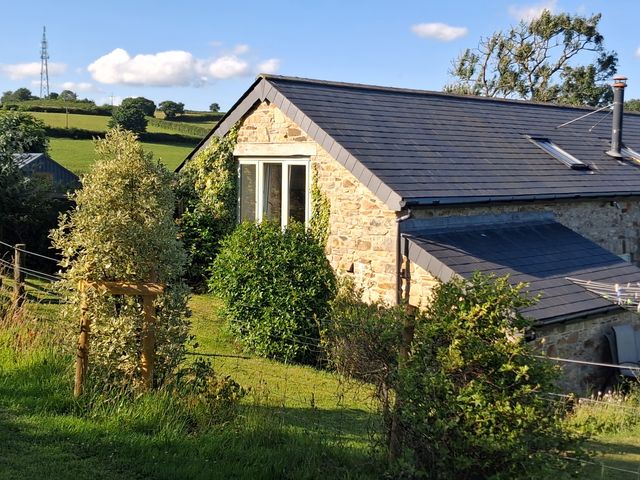 A building with a window and roof in a green field at Woodstone Barn in Whitchurch near Tavistock