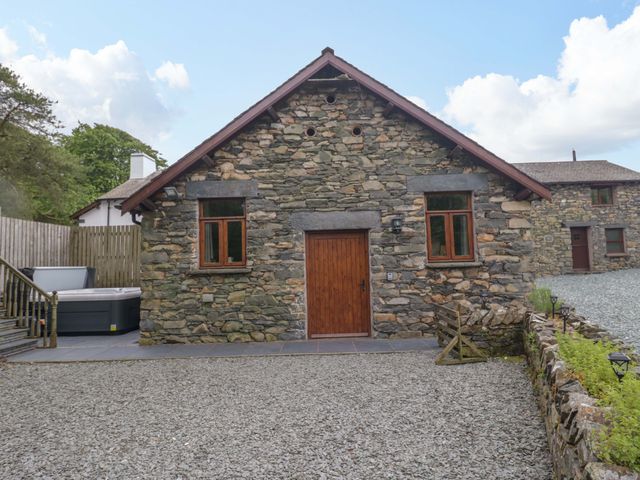 A building with stone walls and a wooden door at Yew Tree Cottage in Torver
