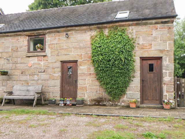 An exterior view with a wooden bench and doors at Horse Shoe Cottage in Threapwood near Cheadle