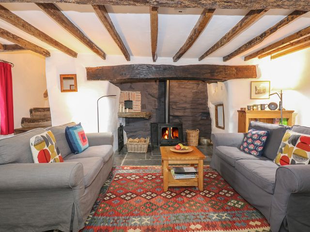 A living room with two gray sofas a wooden coffee table a wood burning stove and exposed wooden ceiling beams at Tafarn Trip in Tan Y Bwlch Maentwrog