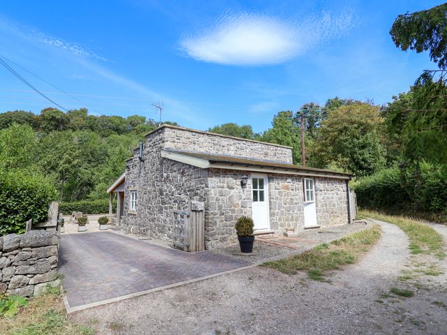 A stone building with a driveway and a plant pot at The Lambing Shed in Dyserth near Prestatyn