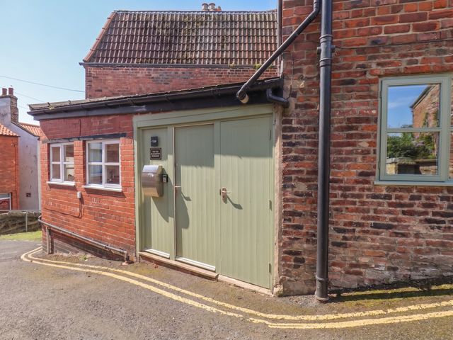 An exterior view showing a green door and windows at The Old Blacksmith's Workshop in Whitby