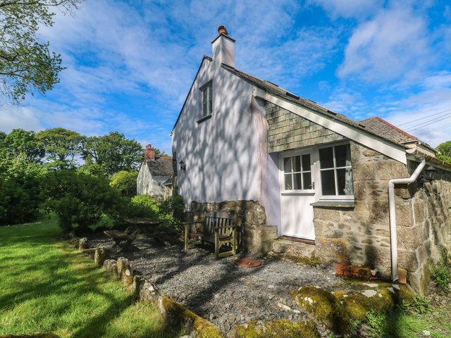 A house with a bench and table surrounded by grass at Longhouse in St Keverne, Lizard Peninsula