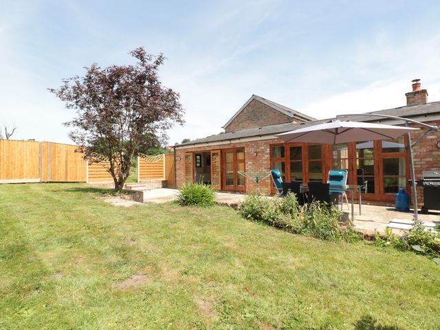 A garden with a tree patio furniture and a barbecue outside a brick house at The Old Dairy in Newnham-on-Severn