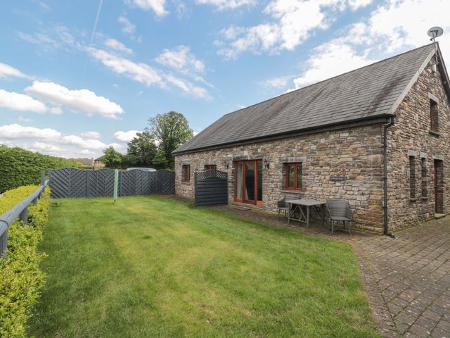 A garden with a stone house and a table with chairs at Longside in Gilwern