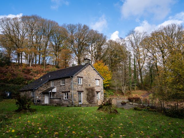 A house with a stone exterior surrounded by trees at Hammerhole in Graythwaite near Hawkshead