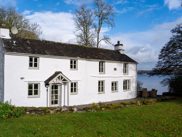 A house near a lake with trees and garden at Hullet Hall Graythwaite near Hawkshead