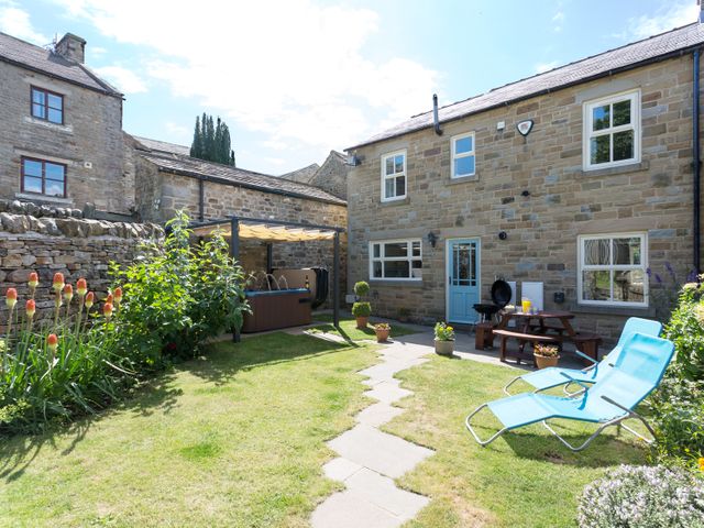 A garden with lawn chairs a picnic table barbeque and plants outside a stone house at 1 Springwater View in Mickleton Teesdale