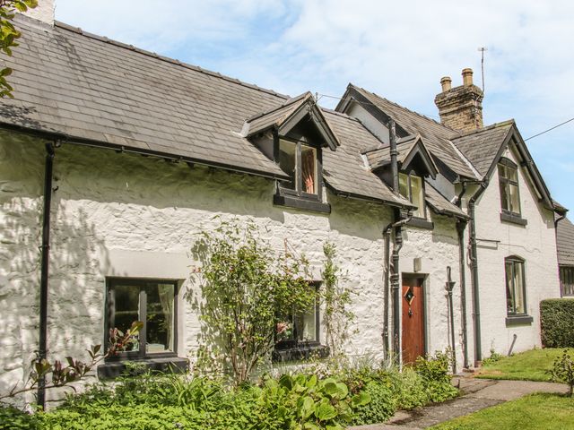 Exterior of a white stone cottage with a slate roof and garden in front at Penymaes Bronygarth near Chirk