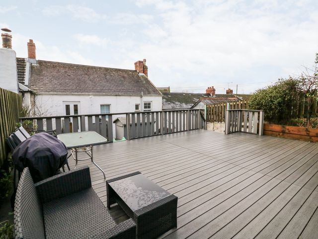 An outdoor deck with patio furniture a table a barbecue grill and railings at The Old Police House in Braunton near Croyde