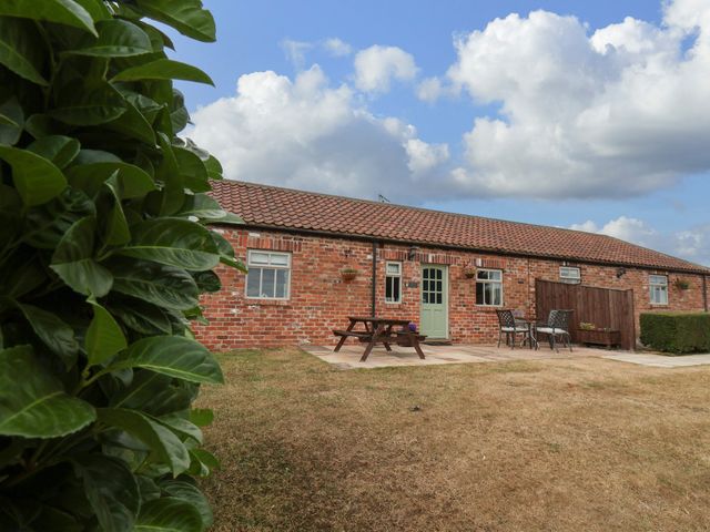A brick building with a table and chairs outside at Beacon in Gerrick near Moorsholm