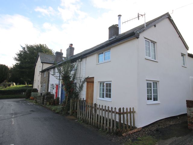 A house with a wooden door and windows at Marigold Cottage in Clun near Bishop's Castle