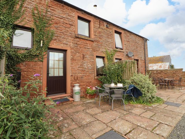 An outdoor area with a stone wall and seating at Horseshoe Cottage in Bolton Low Houses