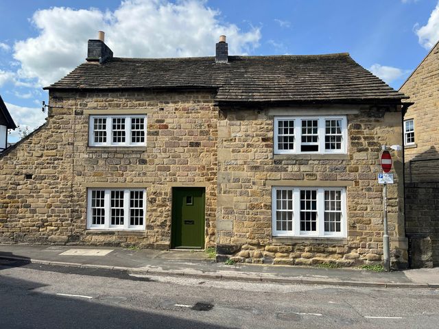 A stone house with multiple windows on a street at Stonecroft in Bakewell