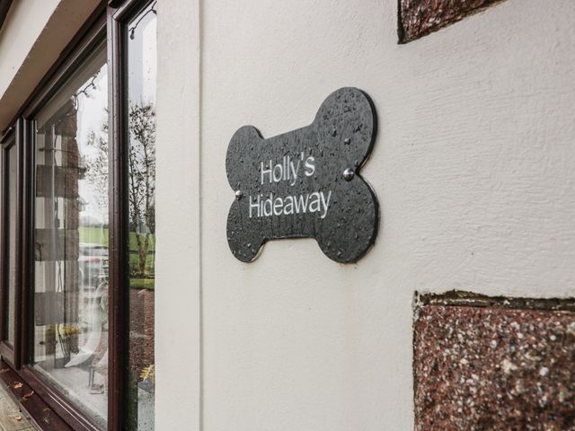 A dog bone shaped sign reading Hollys Hideaway on an exterior wall near a window at Hollys Hideaway Castle Douglas