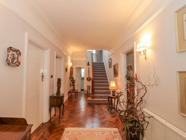 A hallway with wooden flooring a staircase at the end and various pieces of furniture and decorations on the walls at West Ridge in Boscombe