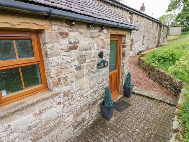 An entrance with stone walls and potted plants at The Hayloft in Alston