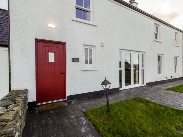 An exterior view of a house with a red door and windows at Finn Cottage