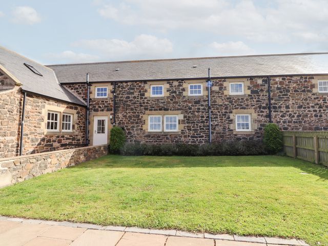 An outdoor view of a stone house with a garden at Granary Stone House Embleton