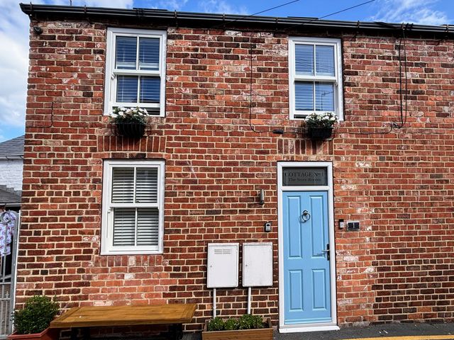 A brick exterior with windows and a blue door at The Store Rooms in Whitby