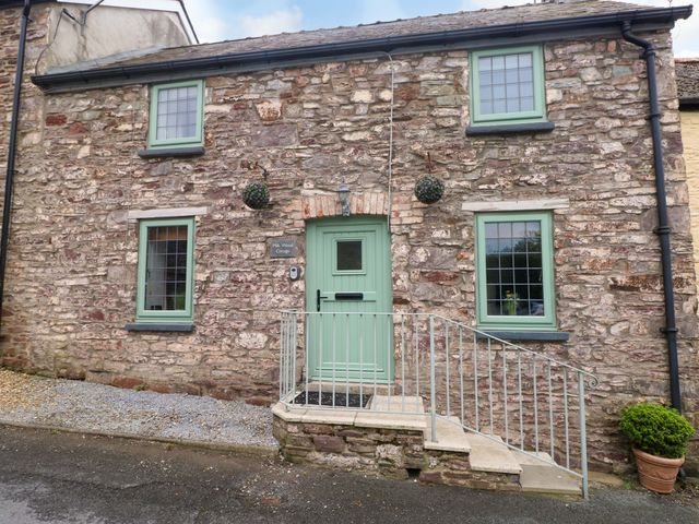 A stone cottage exterior with a green door at Milk Wood Cottage Laugharne