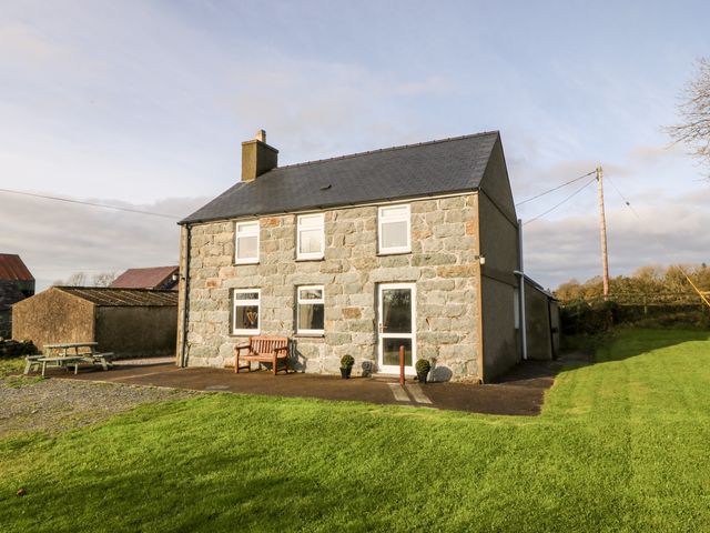 A stone house with six windows a bench and two potted plants on a lawn at Prys Mawr in Chwilog near Criccieth