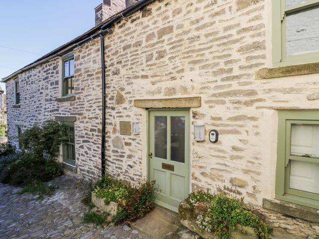 An exterior view of a stone cottage with a door and windows at Castle Hill Cottage in Middleham, Wensleydale
