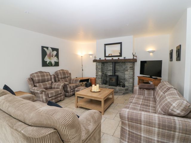 A living room with plaid armchairs sofas a stone fireplace wood stove a wooden coffee table and a television at Rock Lawn Cottage in Kealkill near Bantry County Cork