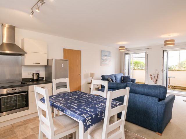 A kitchen and living area with a dining table and chairs and blue sofas at Stones Throw in Charlestown
