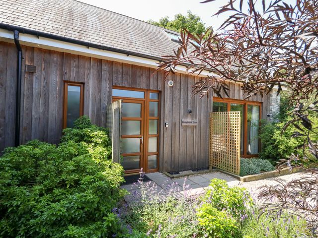 An exterior view of Shepherd Oak near Weymouth with plants and a wooden wall