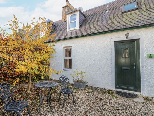 An outdoor area with a table and chairs at Deskford Cottage in Nairn