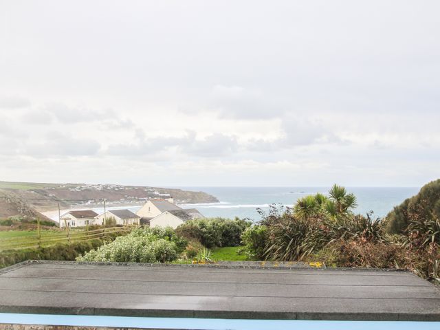 A sea view with houses bushes and a grassy area at Tregiffian Vean in Sennen Cove