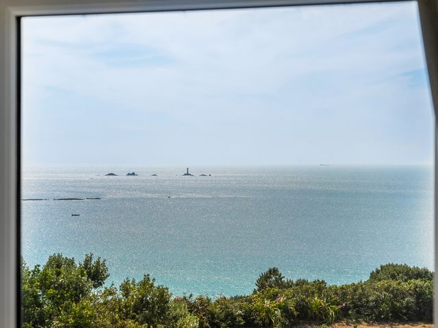 A view of the ocean from a window with a lighthouse at The Lookout in Sennen