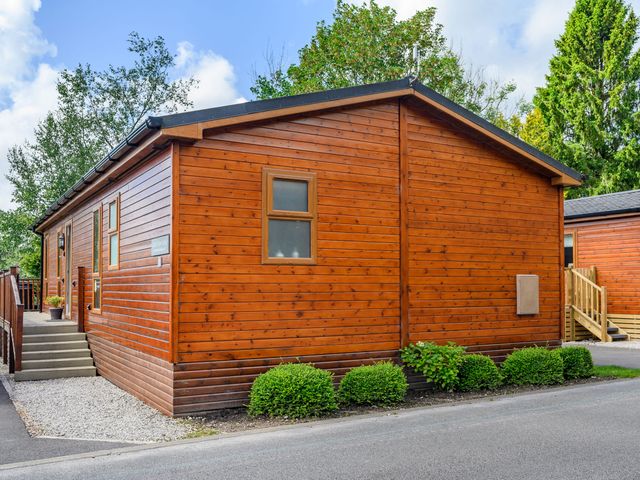 A wooden lodge with a small garden and stairs at Claife View Lodge in Troutbeck Bridge
