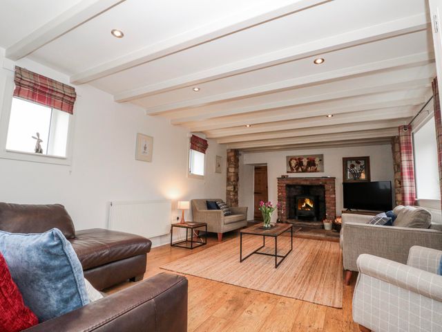 A living room with a fireplace and seating arrangements at Wold Cottage in Hunmanby