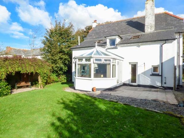 A house with a conservatory and patio area next to a lawn and garden at The Old School House in Lewannick near Launceston