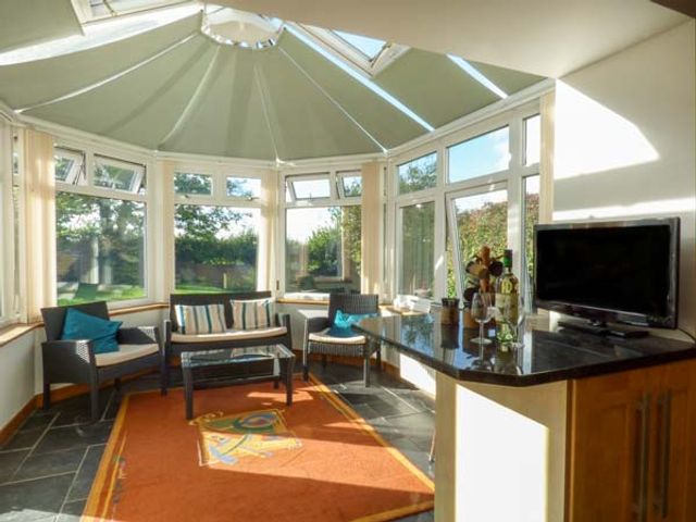 A conservatory with chairs a sofa coffee table and a television on a countertop at The Old School House Lewannick near Launceston