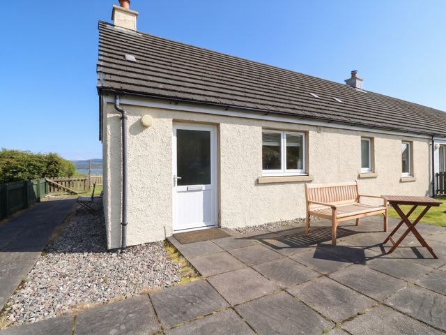 An outdoor view of a house with a door and seating at Sunset Cottage, Craignure, Isle Of Mull