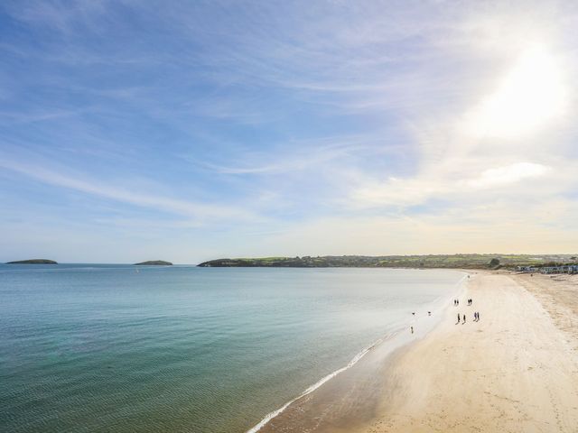 A sandy beach with a few people walking near the water and small islands in the distance at St Tudwals View in Abersoch