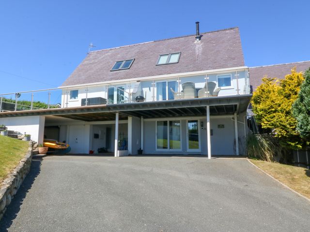A house with a sloped roof and glass balcony overlooking a driveway at St Tudwals View in Abersoch