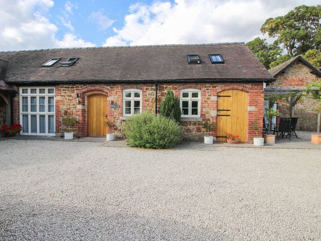 An outdoor area with stone wall and wooden doors at Swallows Cottage Harley near Much Wenlock