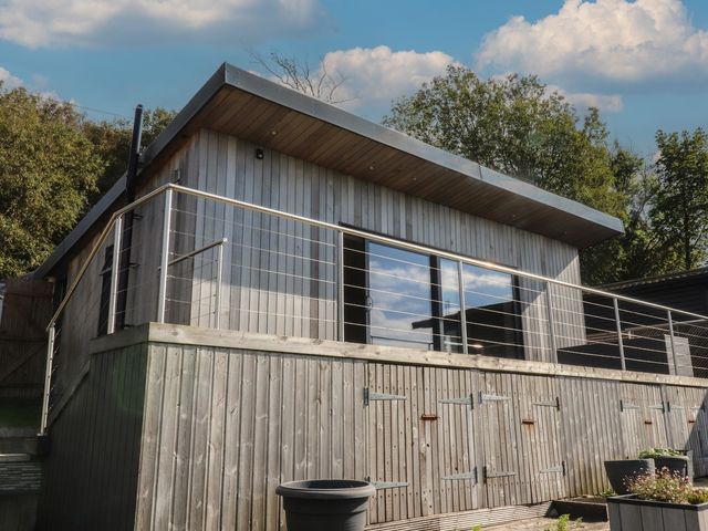 A cabin with a wooden deck and large windows at Heath Hideaway